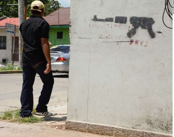 A young man walks past graffiti of a machinegun in San Pedro Sula, the second largest city in Honduras. The city suffers from an extremely high rate of violence with murders committed on a regular basis. Young men are at particular risk.